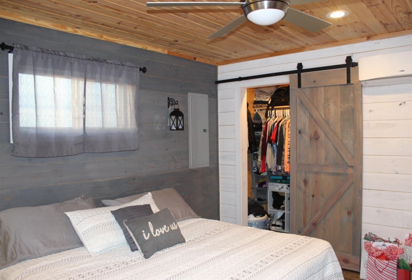 Bedroom featuring wooden ceiling, wood walls, a barn door, a walk in closet, and a closet
