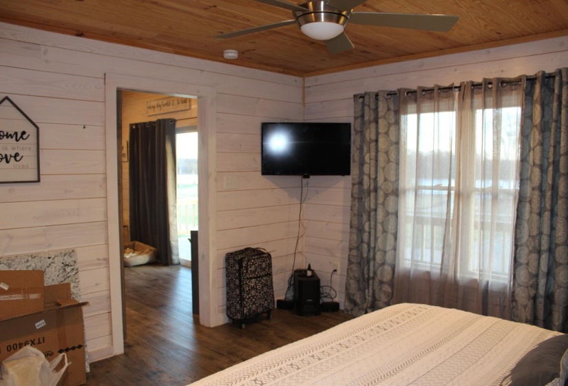 Bedroom featuring wooden ceiling, wooden walls, wood finished floors, and a ceiling fan