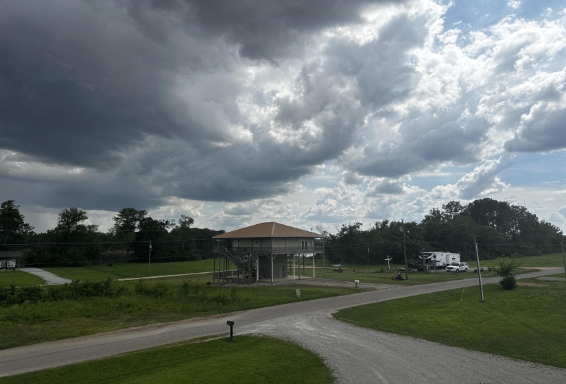 View of community featuring driveway, a yard, stairs, a deck, and a carport