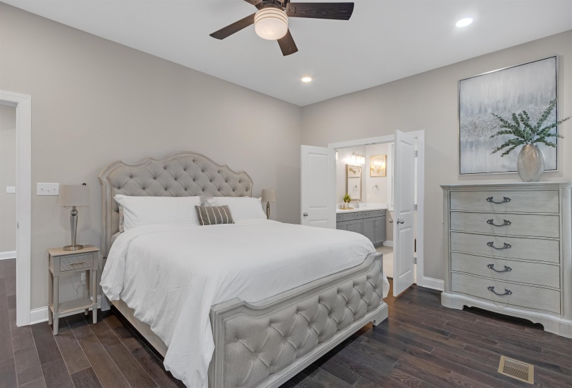 Bedroom featuring ceiling fan, ensuite bathroom, and dark wood-type flooring
