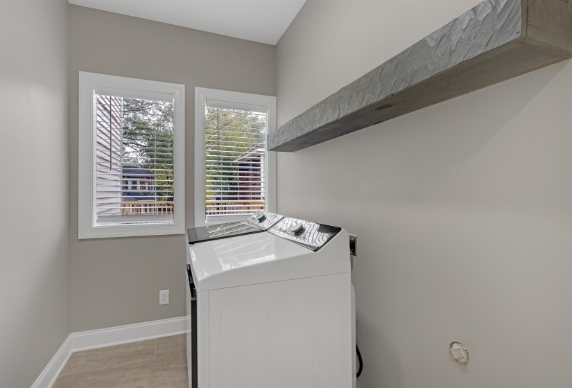 Clothes washing area with light tile patterned floors and washer and clothes dryer