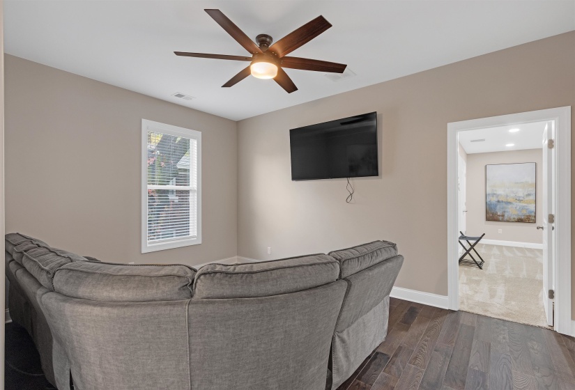 Living room with ceiling fan and dark wood-type flooring