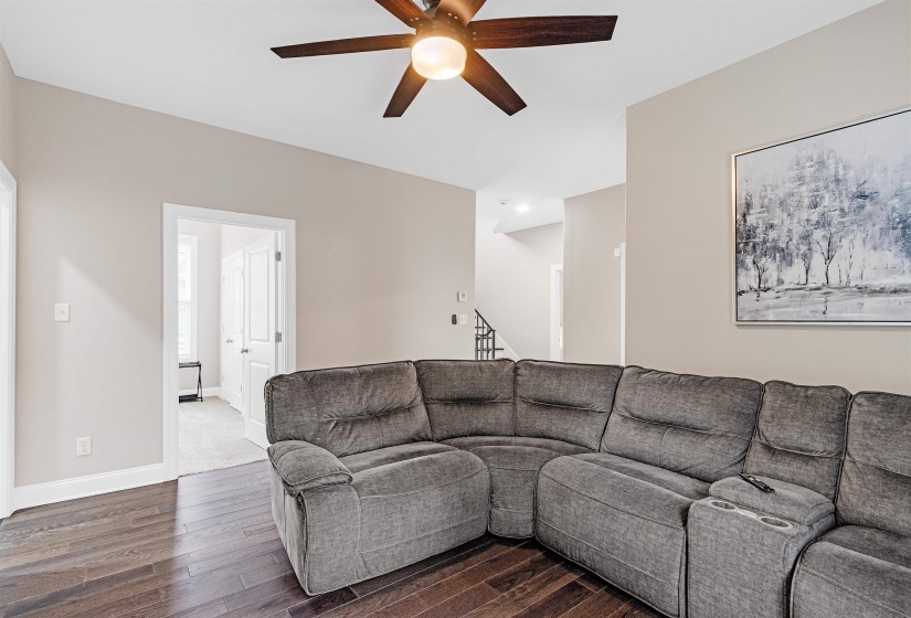 Living room with ceiling fan and dark wood-type flooring