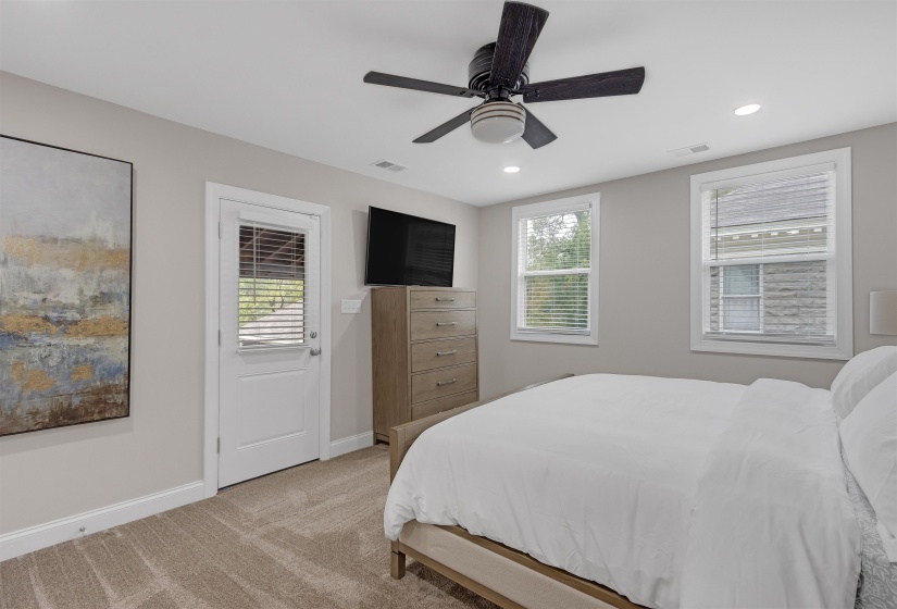 Bedroom featuring multiple windows, ceiling fan, and light colored carpet
