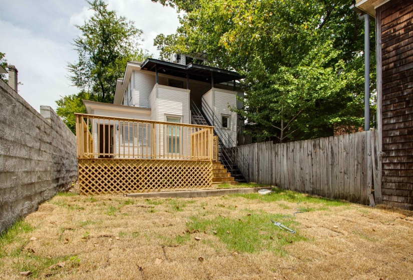 Rear view of property featuring a wooden deck and a yard