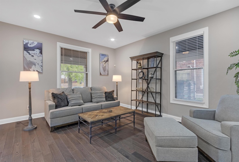Living room with ceiling fan and dark wood-type flooring