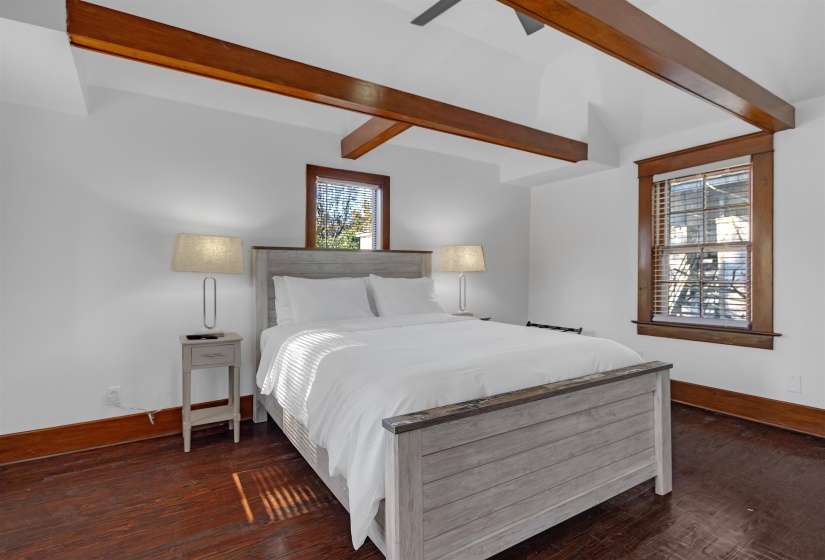 Bedroom featuring ceiling fan, dark hardwood / wood-style flooring, and vaulted ceiling with beams