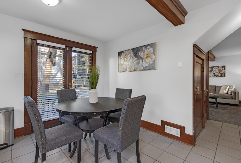 Dining room with light tile patterned floors and vaulted ceiling with beams