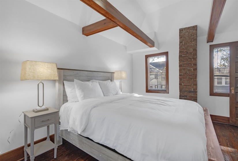 Bedroom with dark hardwood / wood-style flooring and vaulted ceiling with beams