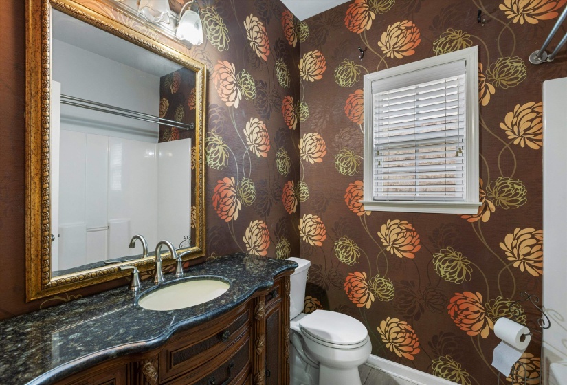 Bathroom featuring a decorative vanity with an integrated sink, polished chrome faucet, and a dark stone countertop