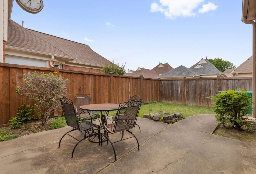 Private backyard featuring a paved patio, wood fencing, and a grass area