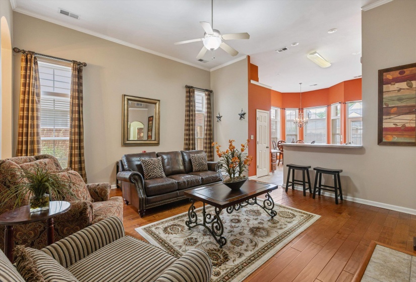 Living area featuring wood-finish flooring, crown molding, and a ceiling fan
