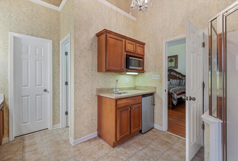 Kitchenette with wood cabinetry, integrated microwave, and compact refrigerator