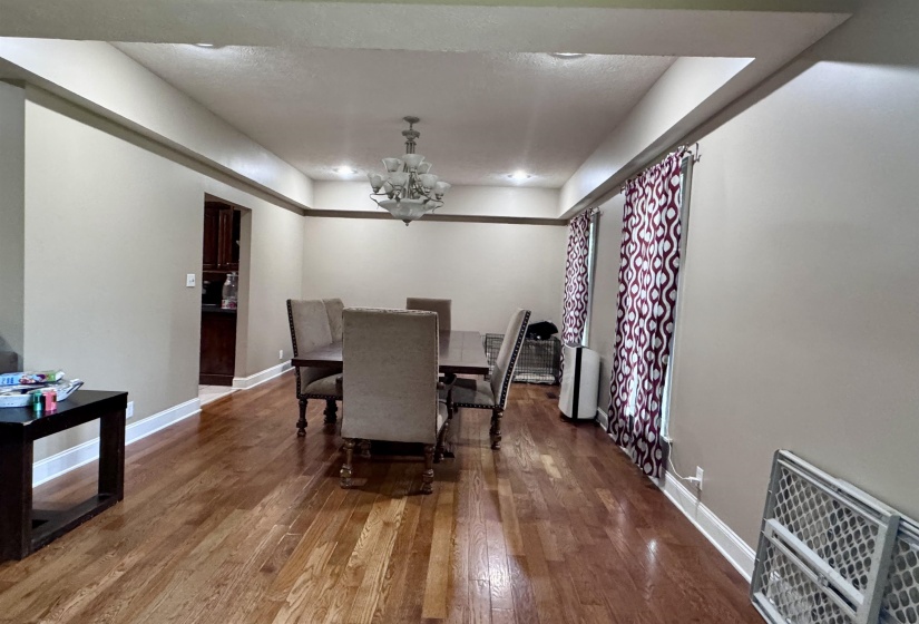 Spacious room featuring wood-finish flooring, recessed lighting, and a tiered chandelier