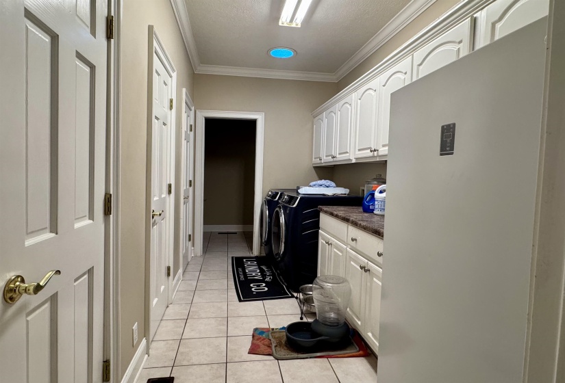 Utility room featuring white cabinetry, a dark countertop, and tile flooring