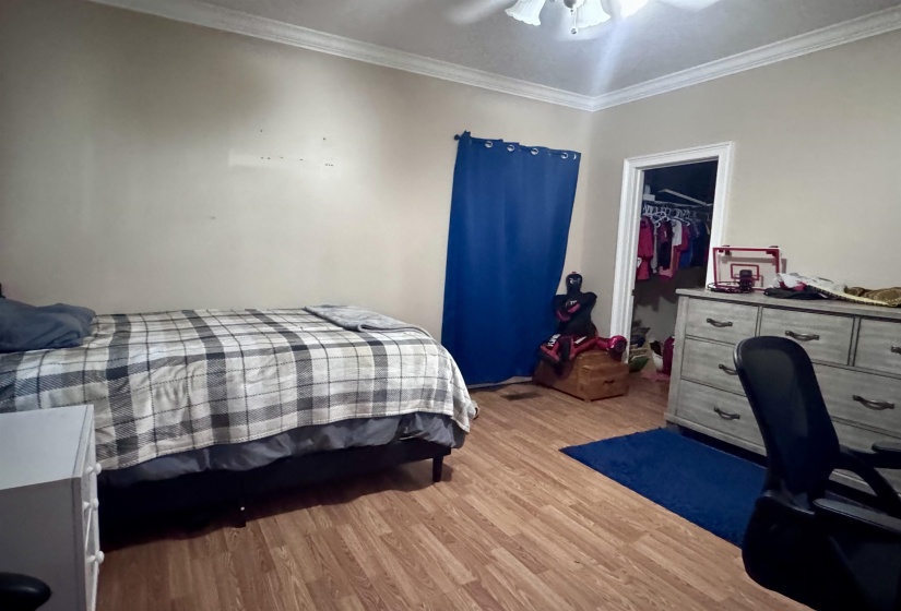 Room featuring wood-finish flooring, crown molding, and a ceiling fan with integrated lighting