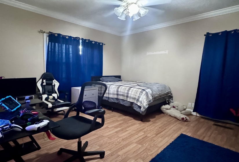 Room featuring wood-finish flooring, a ceiling fan with integrated lighting, and crown molding