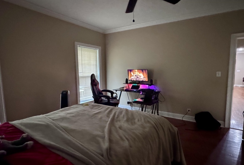 Bedroom featuring wood-finish flooring, neutral wall tones, crown molding, and a ceiling fan
