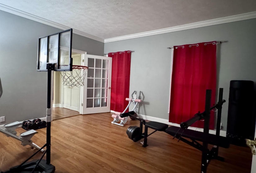 Room featuring wood-finish flooring, neutral gray walls, and white crown molding