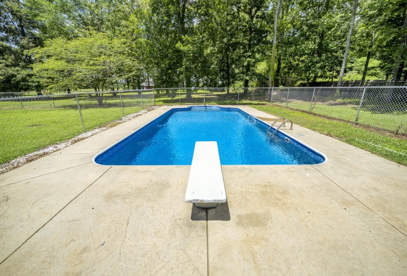 Rectangular in-ground swimming pool with a diving board and concrete surround