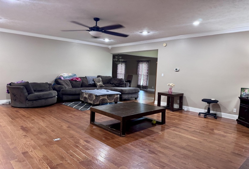 Spacious living area featuring wood-finish flooring, recessed lighting, and crown molding