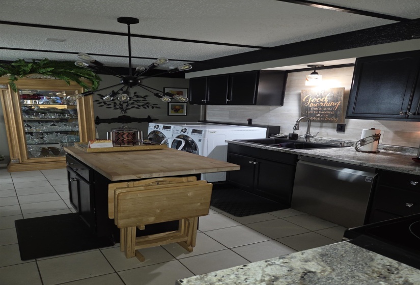 Kitchen featuring dark cabinetry, light-toned tile flooring, and a stone-finish countertop