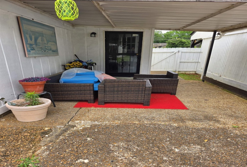 Covered outdoor patio area featuring a white corrugated metal roof and a solid security door