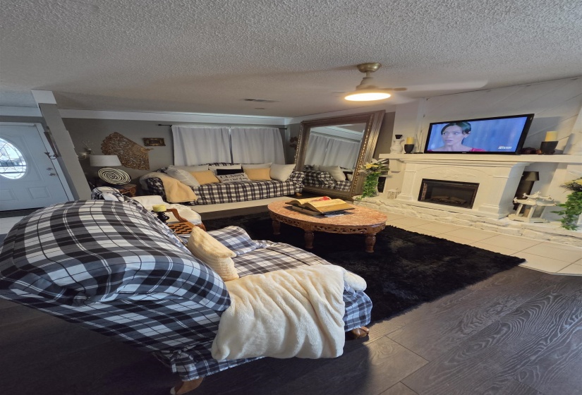 Living area featuring dark wood-finish flooring and a white brick fireplace