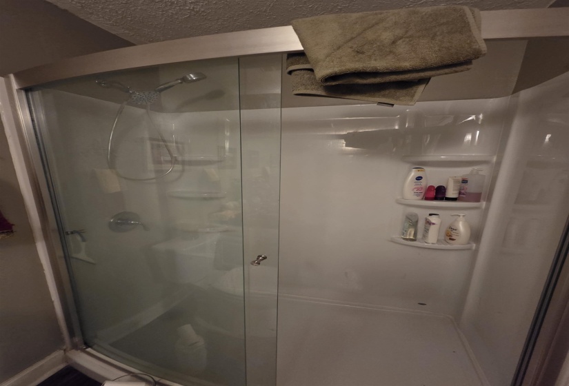 Corner shower enclosure featuring clear glass panels and a white composite base