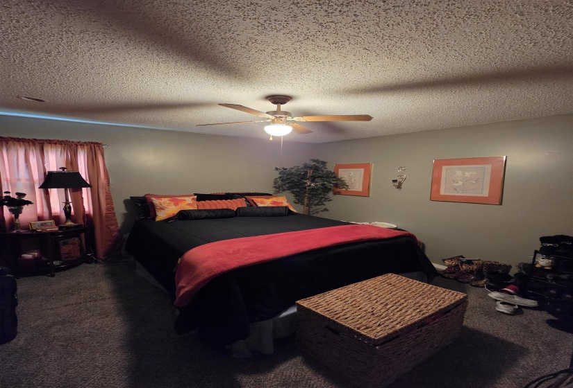 Bedroom featuring neutral wall paint, textured ceiling, and a ceiling fan with light fixture