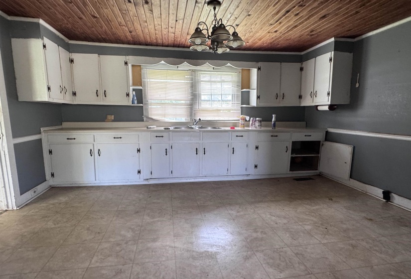 Kitchen featuring a wood-panel ceiling, white cabinetry with black hardware, a dual-basin sink, and tiled flooring
