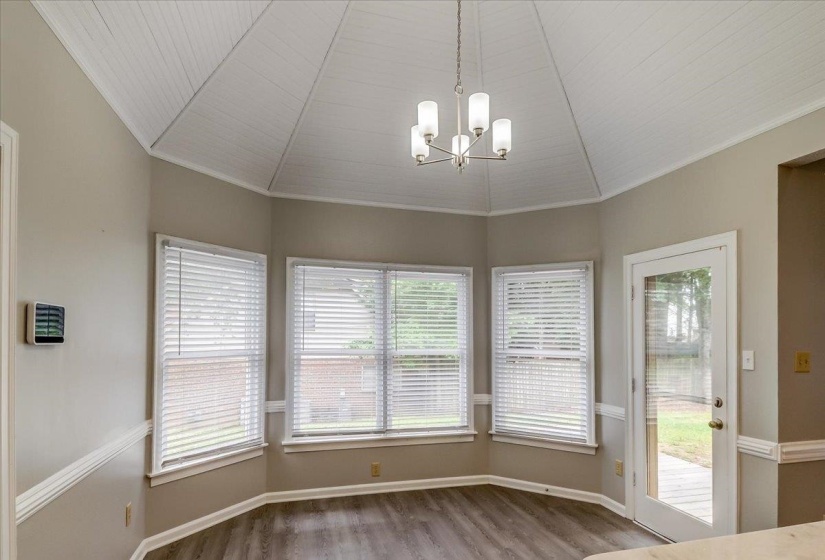 Breakfast nook with vaulted beadboard ceiling, contemporary chandelier, and wood-finish flooring