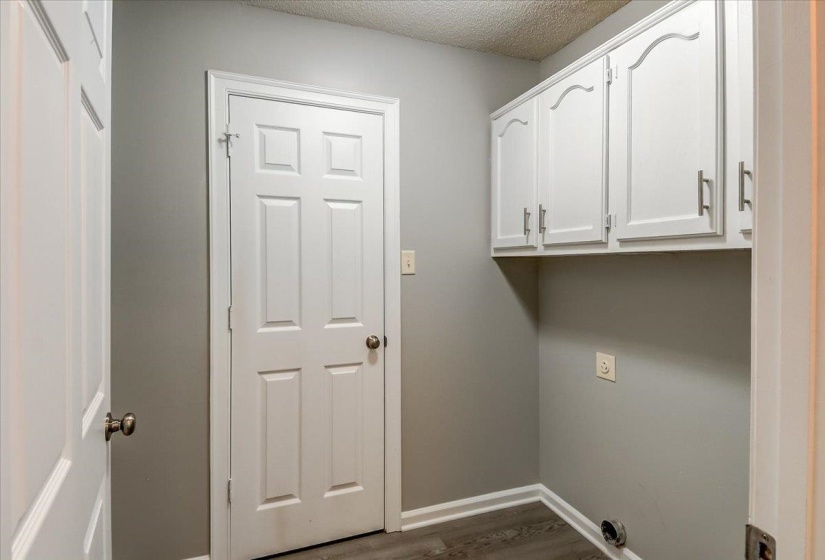 Laundry area featuring white cabinetry with brushed nickel pulls, wood-finish flooring, and light gray wall paint