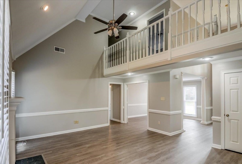 Spacious interior featuring a vaulted ceiling, wood-finish flooring, and a second-story overlook with a white balustrade