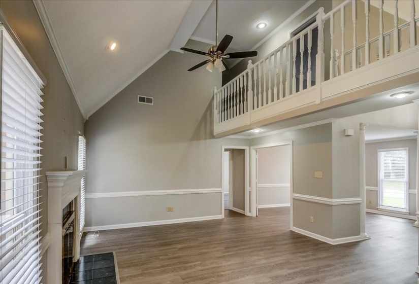 Open-concept living space featuring wood-finish flooring and a white-painted fireplace mantel with a dark tile hearth