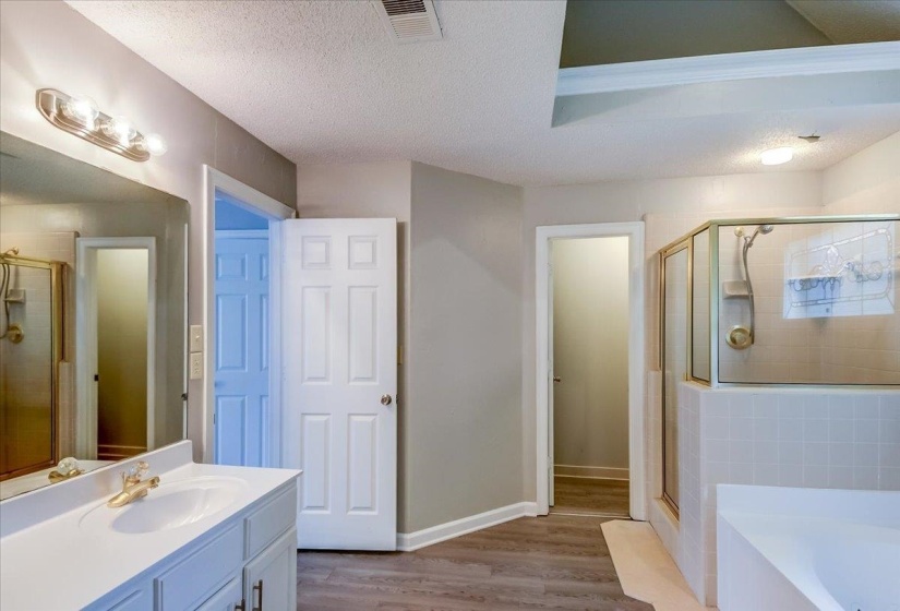 Bathroom featuring a white vanity with integrated sink, brass-finish faucet, and a large wall mirror