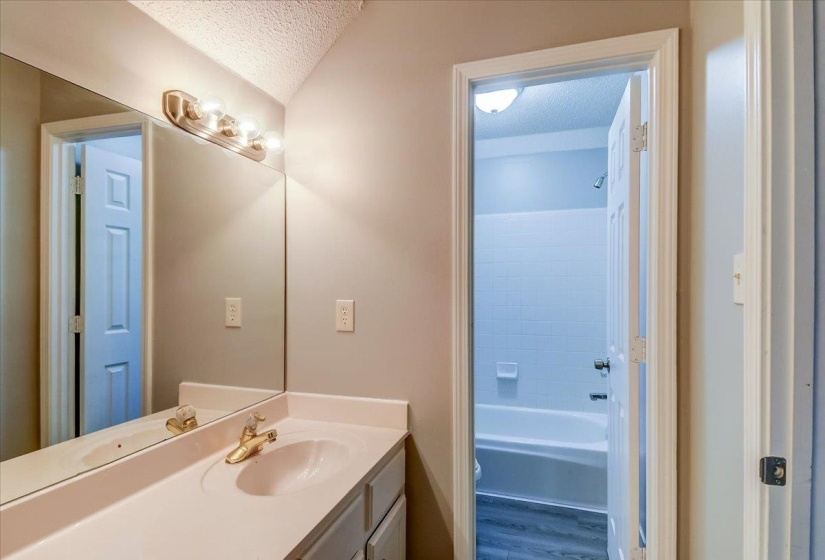 Bathroom vanity featuring a single basin sink and a gold-tone faucet