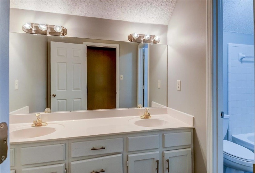 Dual vanity with integrated sinks, brushed gold-finish fixtures, and a large wall-mounted mirror