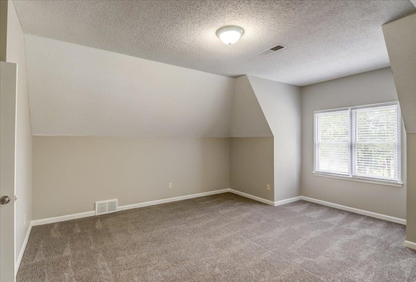 Carpeted room featuring a double window with white blinds, recessed wall areas, and a ceiling-mounted light fixture
