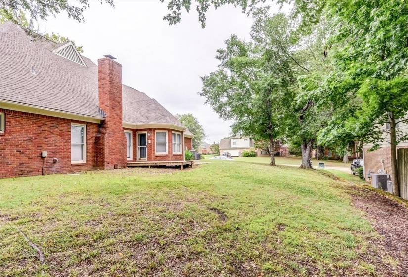 Expansive sloped lawn with mature trees and a brick exterior residence