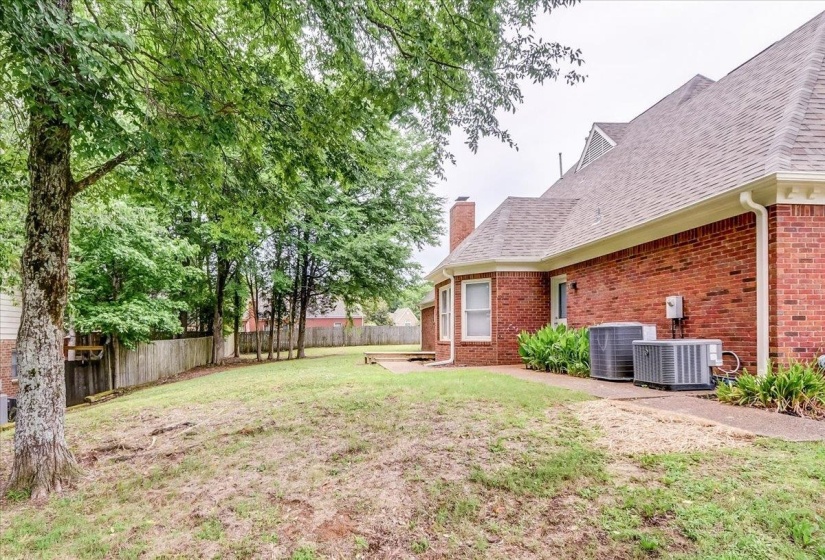 Spacious rear yard with mature trees and a wooden privacy fence