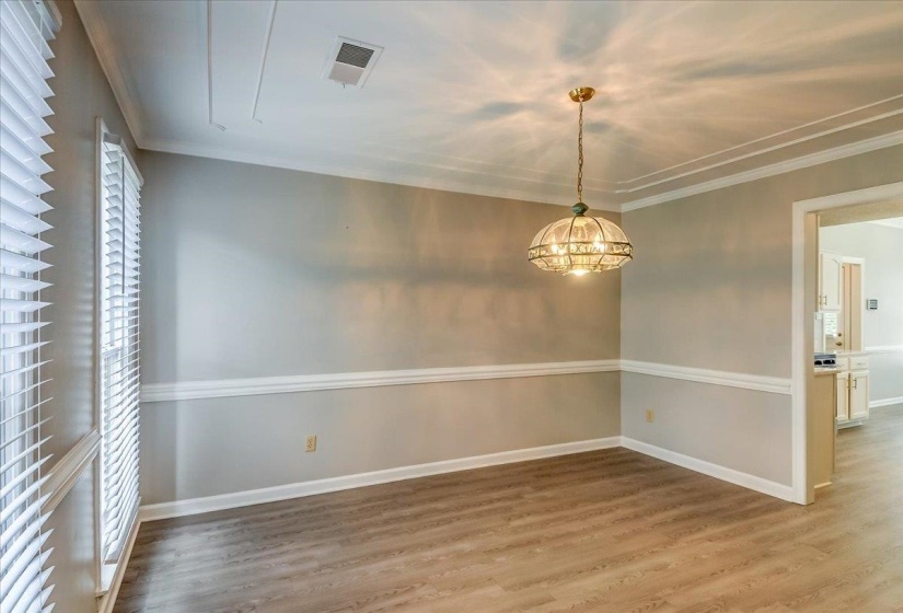 Spacious room featuring wood-finish flooring, a tiered ceiling, and a decorative chandelier