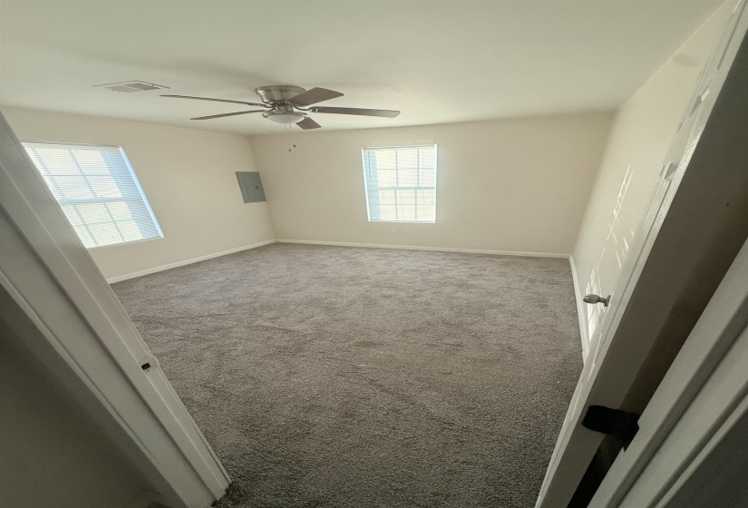 Carpeted room featuring two windows with horizontal blinds, a ceiling fan with light, and light-colored walls