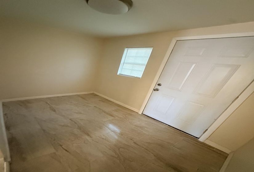 Entry area featuring wood-look tile flooring, neutral wall tones, a paneled door, and a horizontal window with blinds