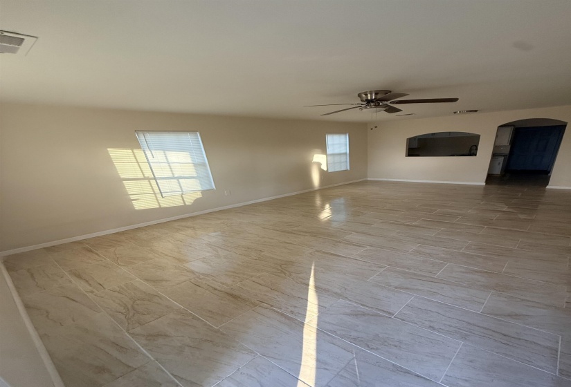 Spacious room with large-format tile flooring, neutral wall tones, and multiple windows