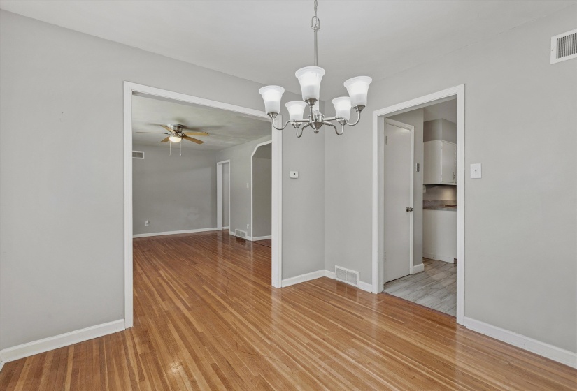Dining area featuring wood-finish flooring, a contemporary five-light chandelier, and light gray wall paint