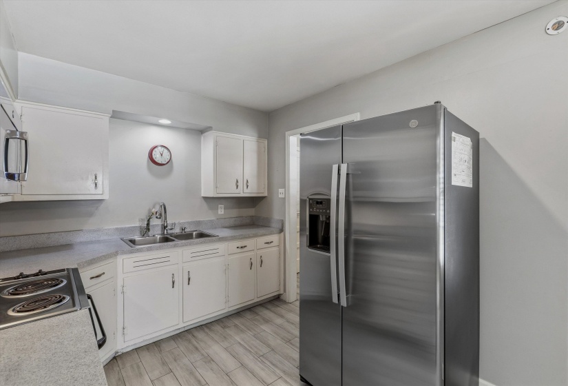 Kitchen featuring a double basin stainless steel sink, white cabinetry with silver hardware, gray countertops, and wood-finish flooring