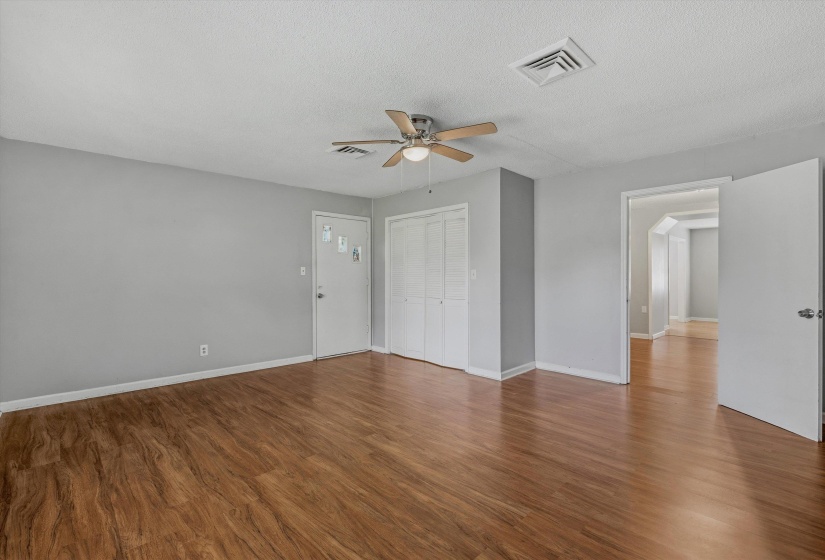 Spacious room featuring wood-finish flooring, light gray walls, and a ceiling fan with integrated lighting