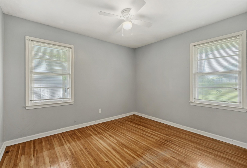 Room featuring wood-finish flooring, light gray walls, and white trim
