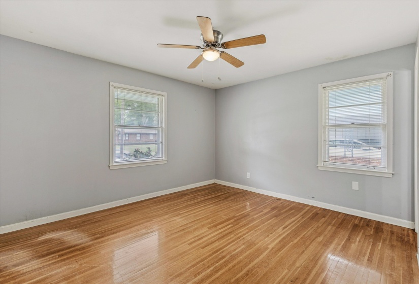 Spacious room featuring wood-finish flooring, light gray walls, and two white-framed windows
